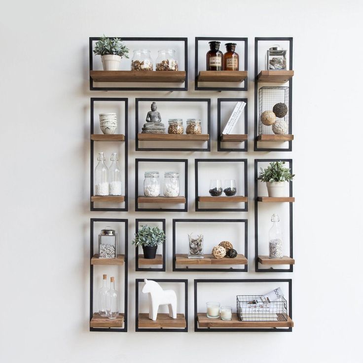 several shelves with plants and vases on them against a white wall in a room