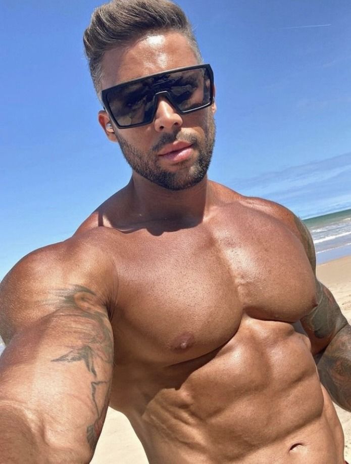 a shirtless man on the beach wearing sunglasses