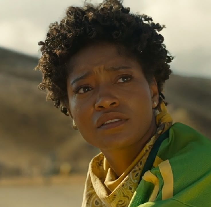 a close up of a person wearing a green and yellow shirt with mountains in the background