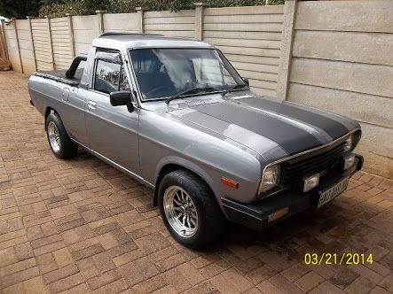 a gray pick up truck parked in front of a fence