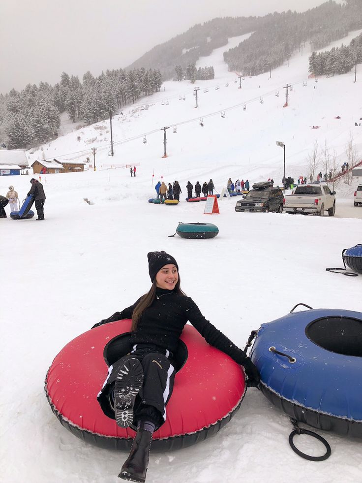 a woman sitting on top of a snow covered ground next to a red and blue sled