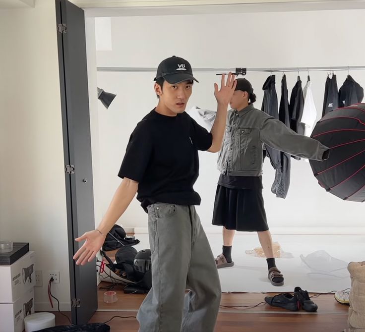 two young men standing in front of a mirror with umbrellas hanging from the ceiling