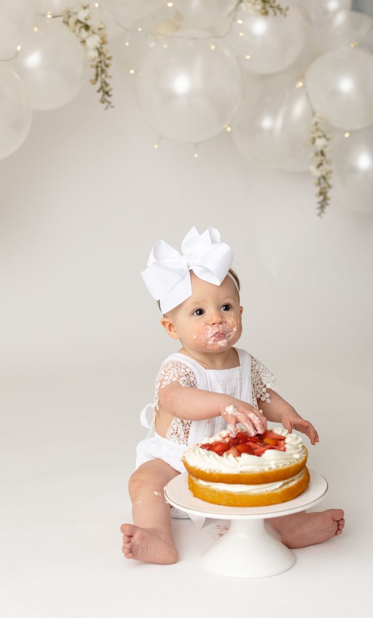 a baby sitting on the floor with a cake