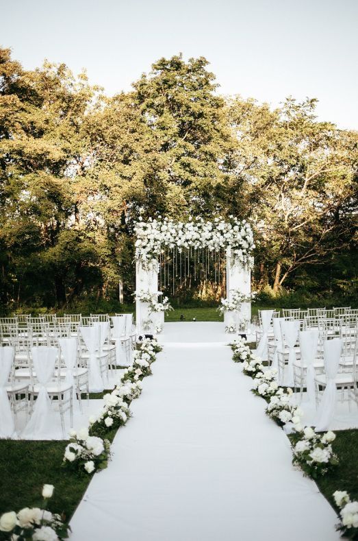 an outdoor wedding ceremony with white flowers and chairs set up for the aisle to be married