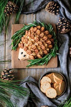 an animal made out of bread and nuts on a cutting board next to pine cones