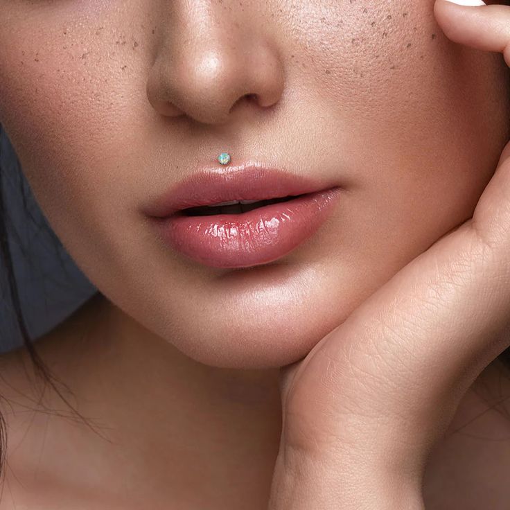 a woman with freckles on her face and hand near her cheek, posing for the camera