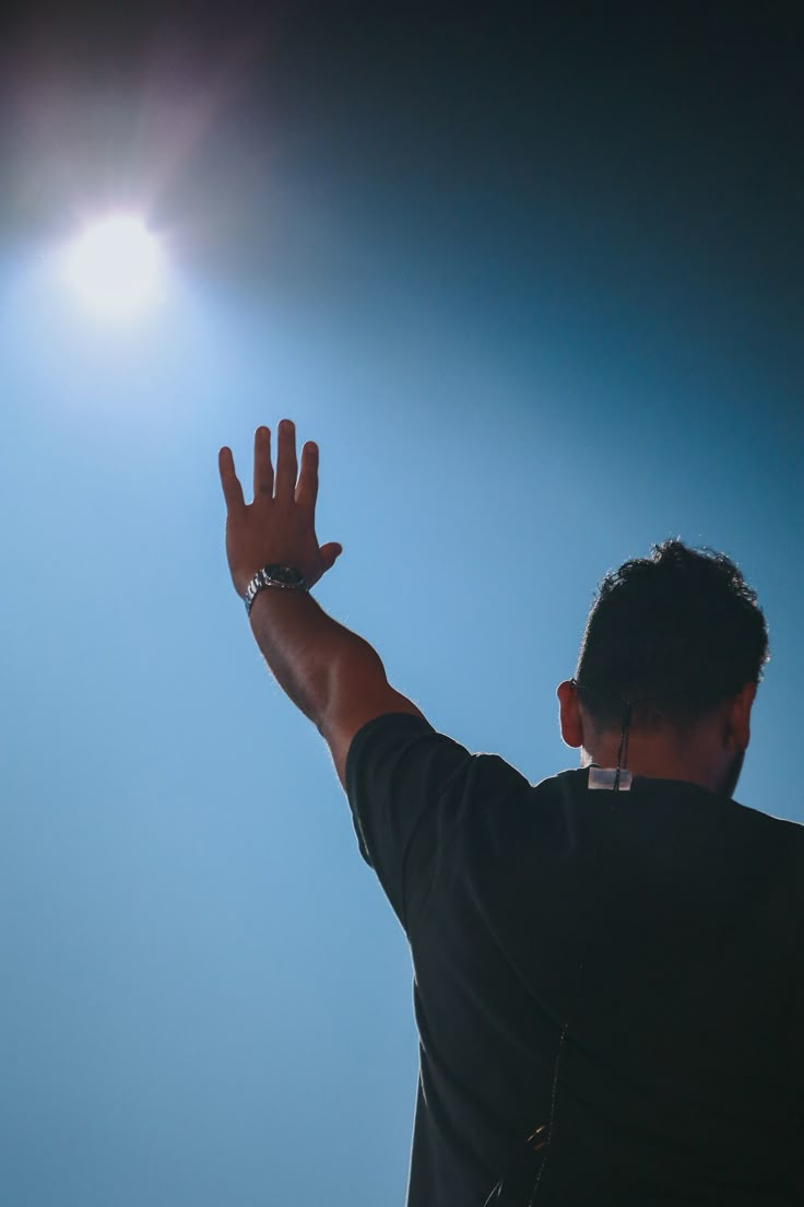 a man reaching up to catch a frisbee in the air with his hand