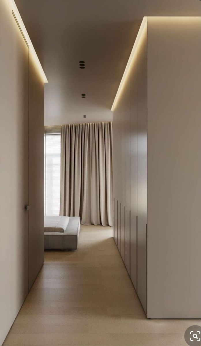 an empty room with white walls and beige drapes on the windowsills is lit by recessed lights