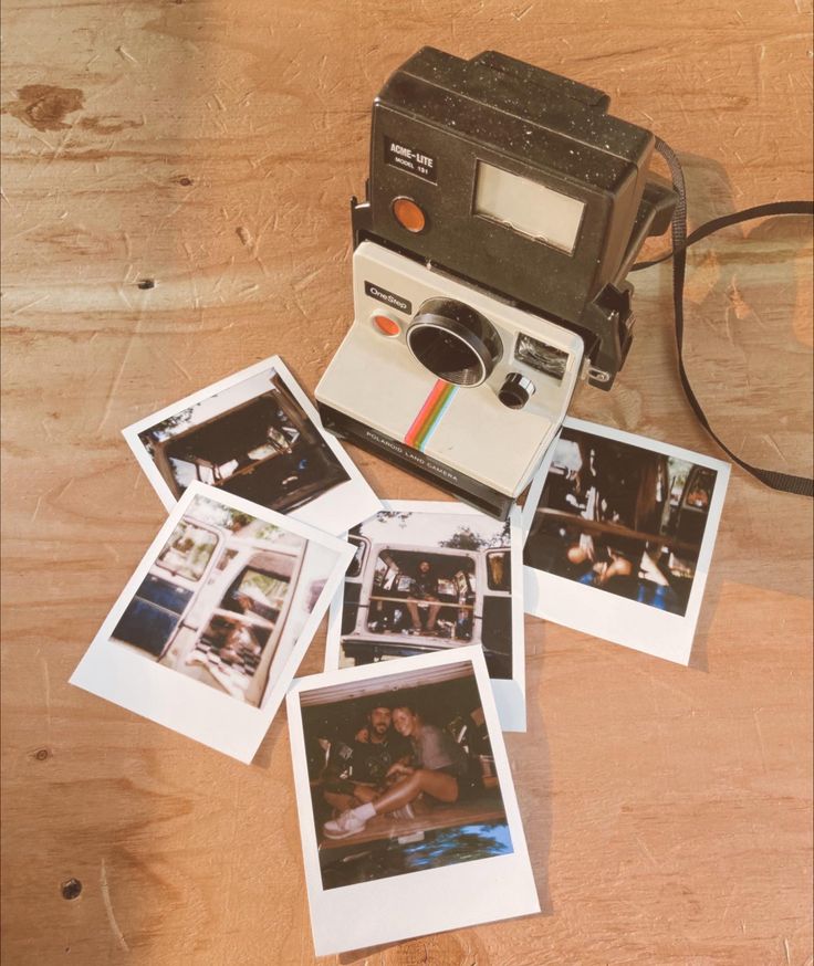 polaroid camera sitting on top of a wooden table next to several polaroid pictures