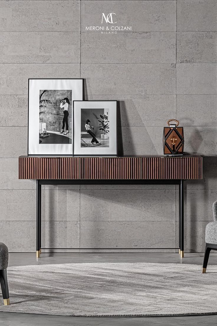 a modern console table with two pictures on it and a chair in front of it