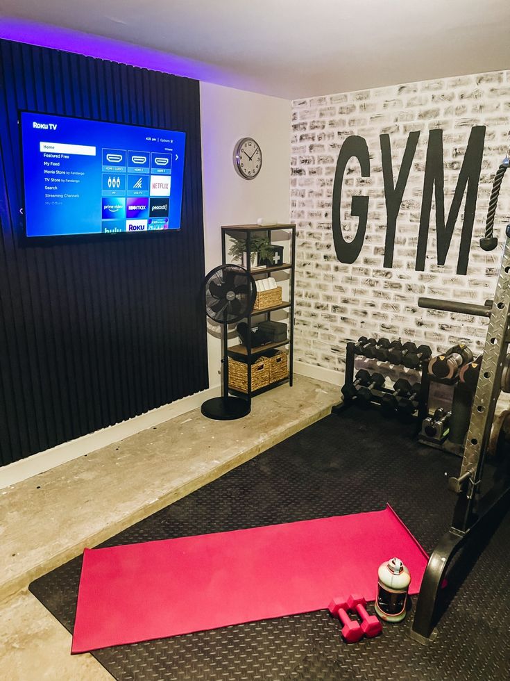 there is a gym room with equipment on the floor and a large screen in the background