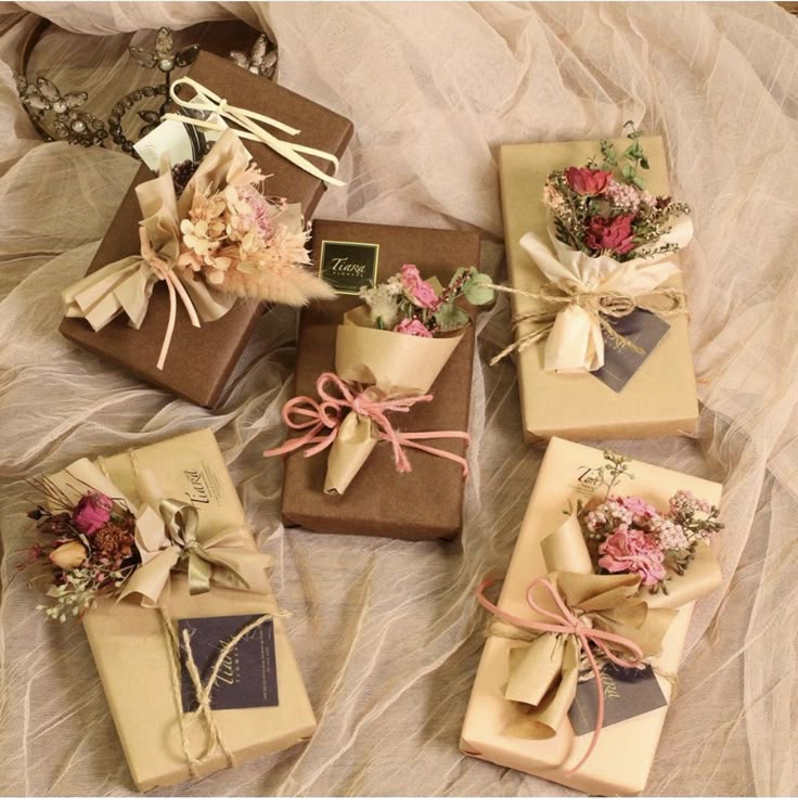 six wrapped gift boxes with flowers and ribbons tied around them on top of a bed