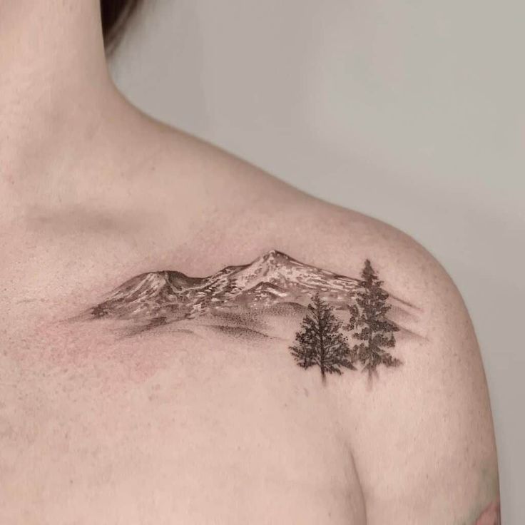 a man's chest with mountains and trees tattoo on his left side ribcage