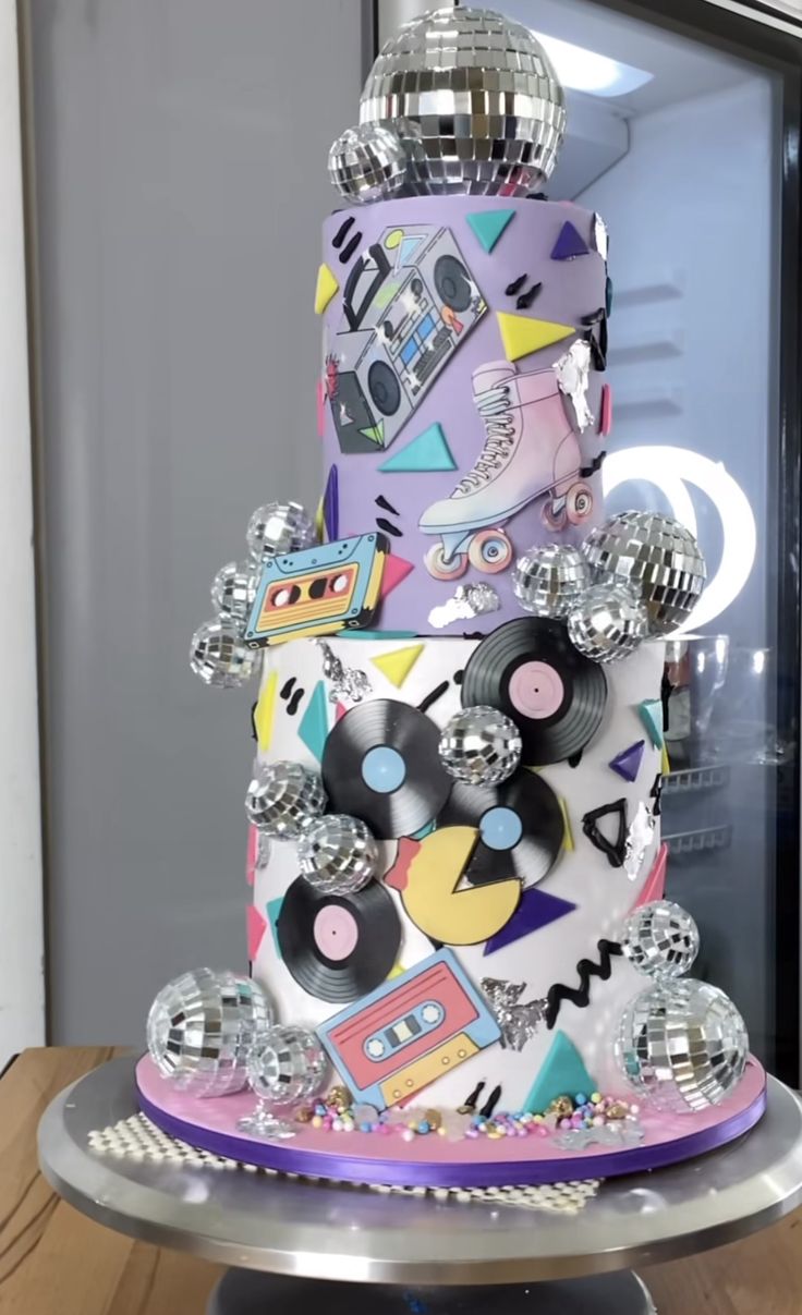 a multi - tiered cake decorated with disco balls and cassettes