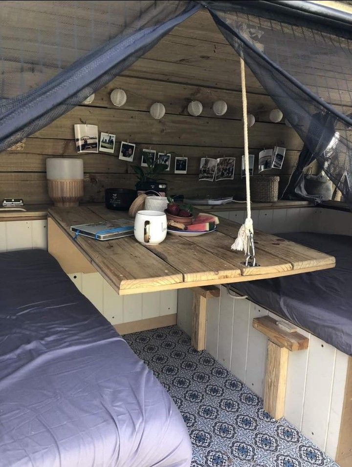 a bed sitting under a tent next to a wooden table