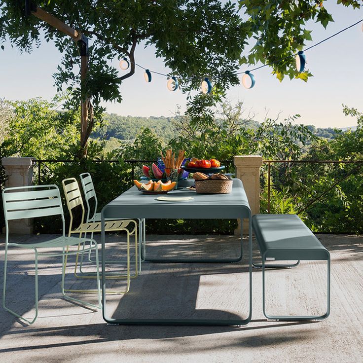 an outdoor table and chairs with fruit on it