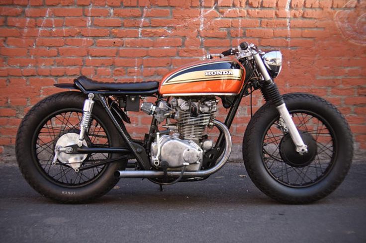 an orange and black motorcycle parked next to a brick wall