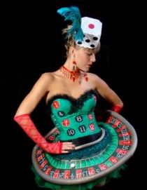 a woman in a green dress holding a black and red wheel of fortune game costume