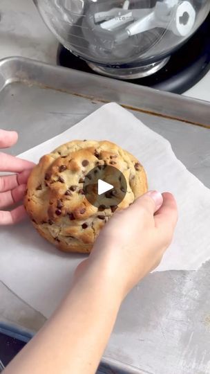 a person holding a cookie on top of a piece of paper next to a frying pan