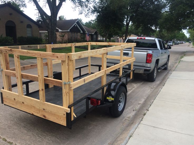 a truck with a trailer attached to it parked on the side of a road next to a house