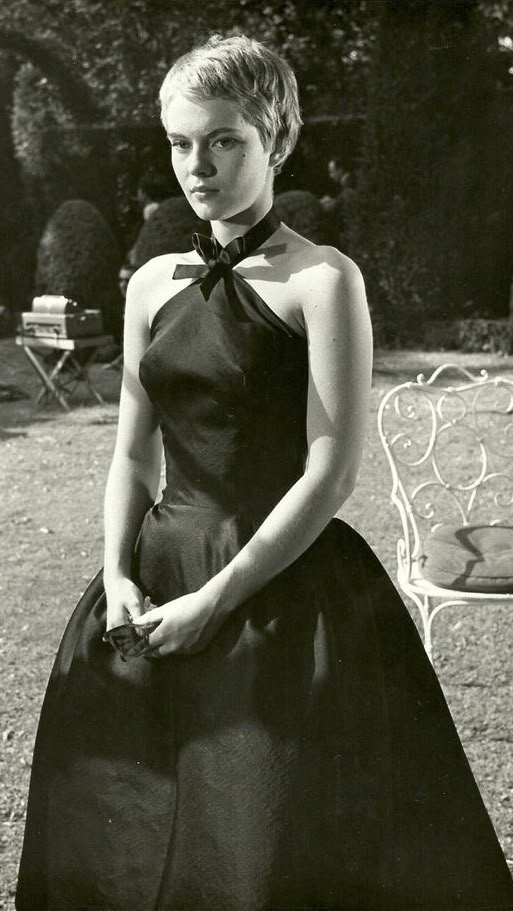 a black and white photo of a woman in a dress with a bow around her neck