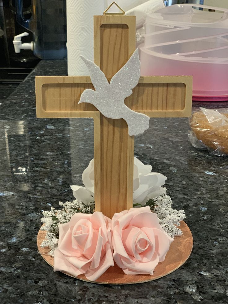 a wooden cross sitting on top of a table next to pink roses and paper towels