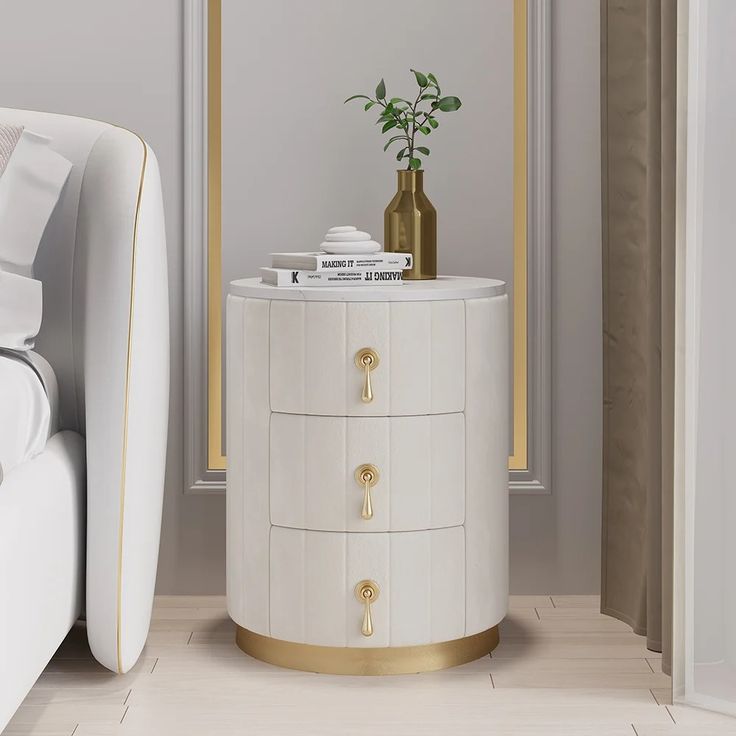 a white and gold side table with a plant on it next to a bed in a room