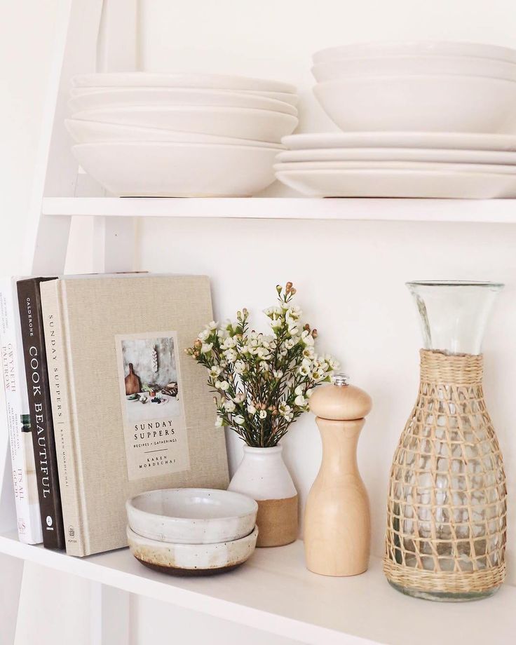 a shelf with plates, vases and books on it next to a bookcase