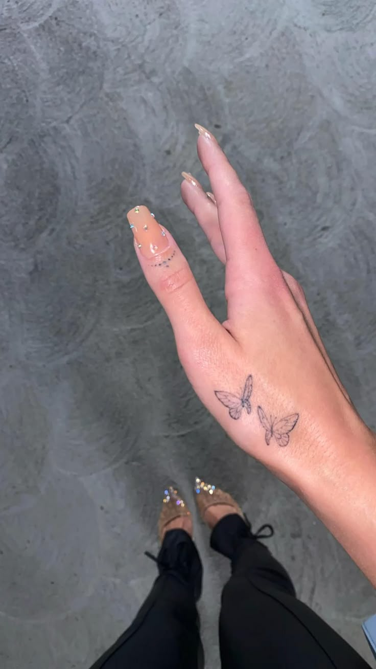 a woman's hand with a butterfly tattoo on her left thumb and right foot