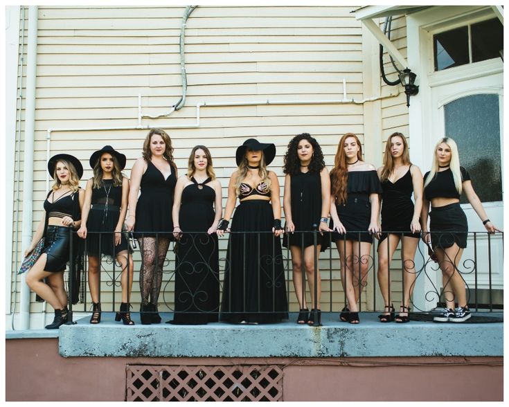 a group of women standing next to each other on top of a metal fence in front of a building