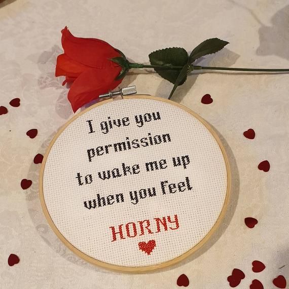 a red rose sitting on top of a table next to a cross stitch hoop with the words, i give you permision to wake me up when you feel