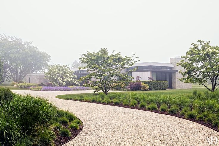 a large house sitting on top of a lush green field next to a gravel road