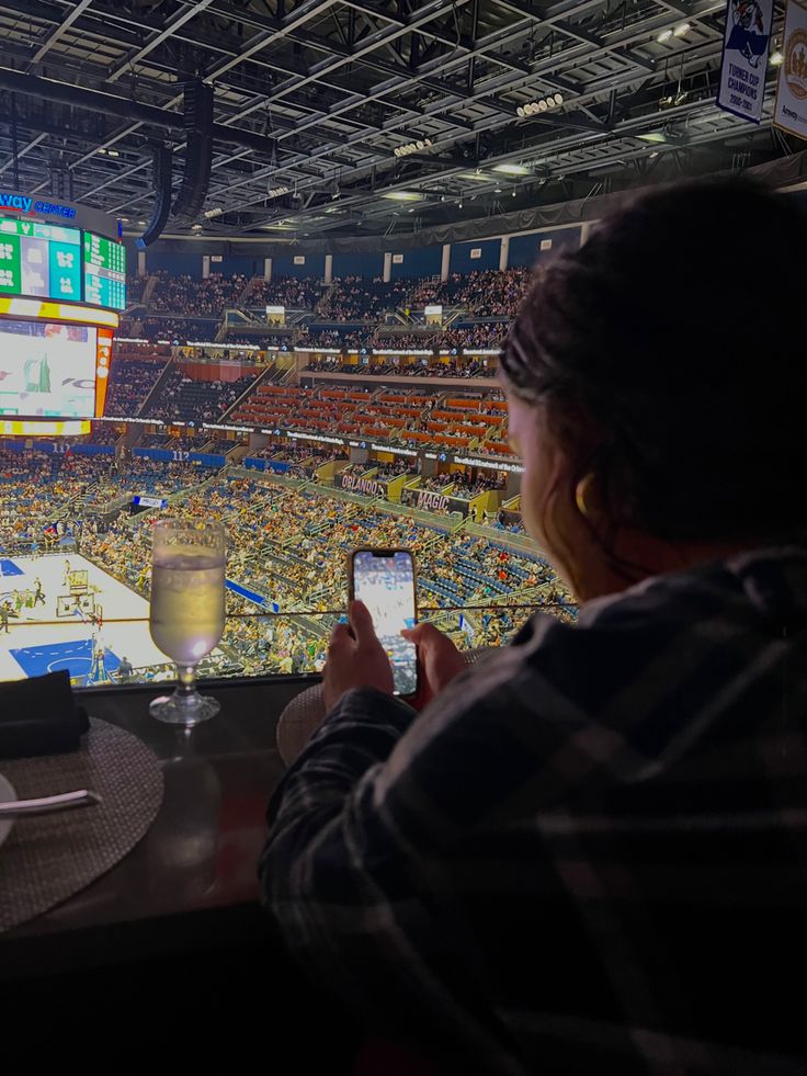 a person sitting at a table with a cell phone in front of them and an arena full of people