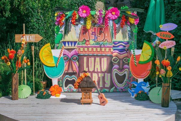 an outdoor stage set up with flowers, signs and decorations for a luau party