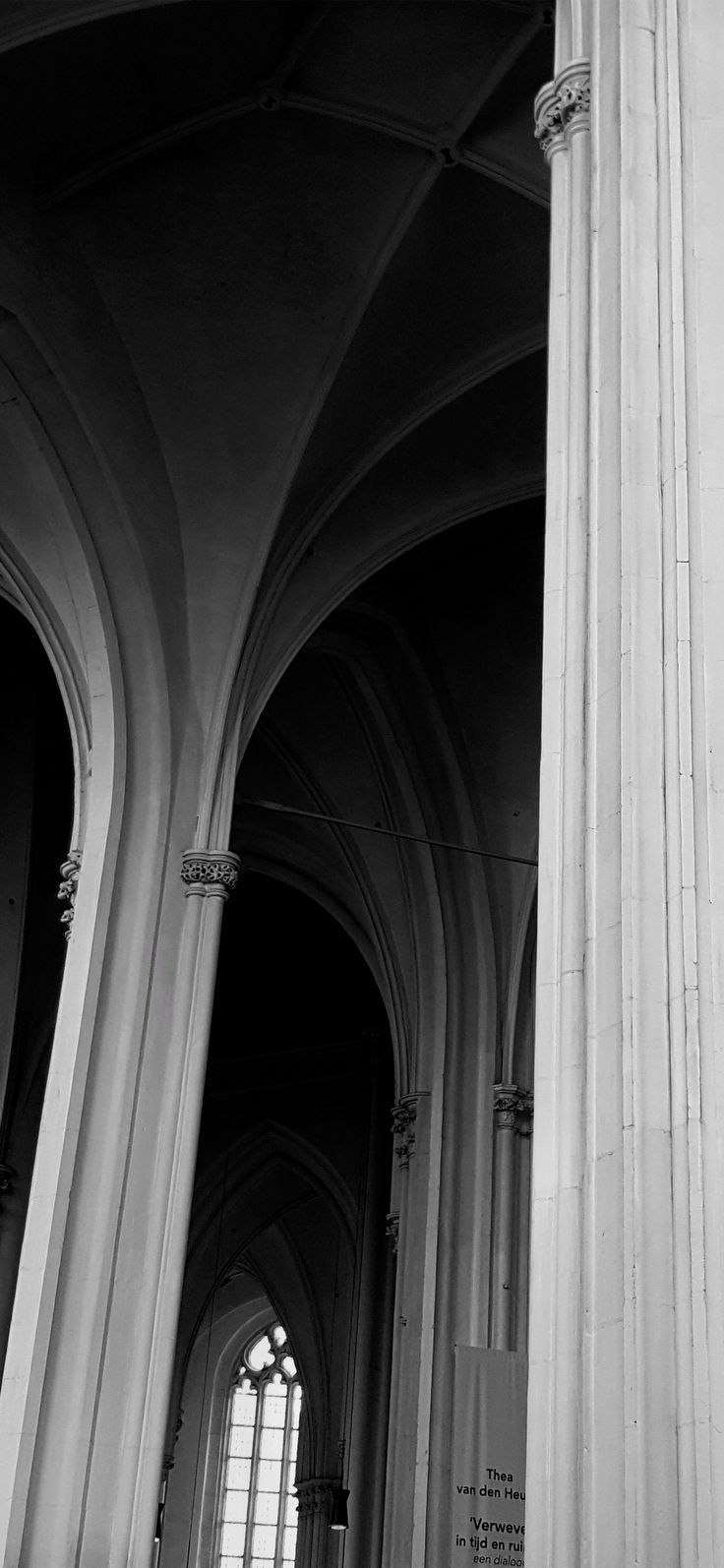 black and white photograph of the inside of a church with columns, windows and graffiti on the walls