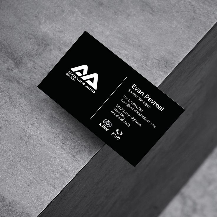 a black and white business card sitting on top of a wooden table next to a wall