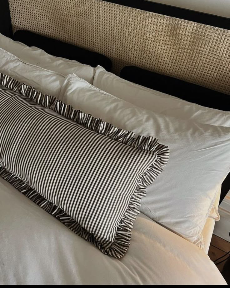 a black and white striped pillow sitting on top of a bed