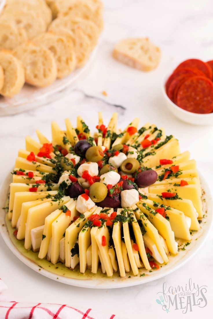 a platter filled with cheese and olives next to crackers on a table