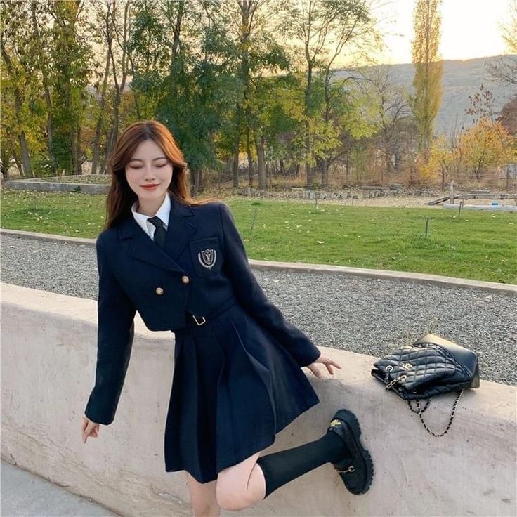 a woman in a school uniform leaning against a wall