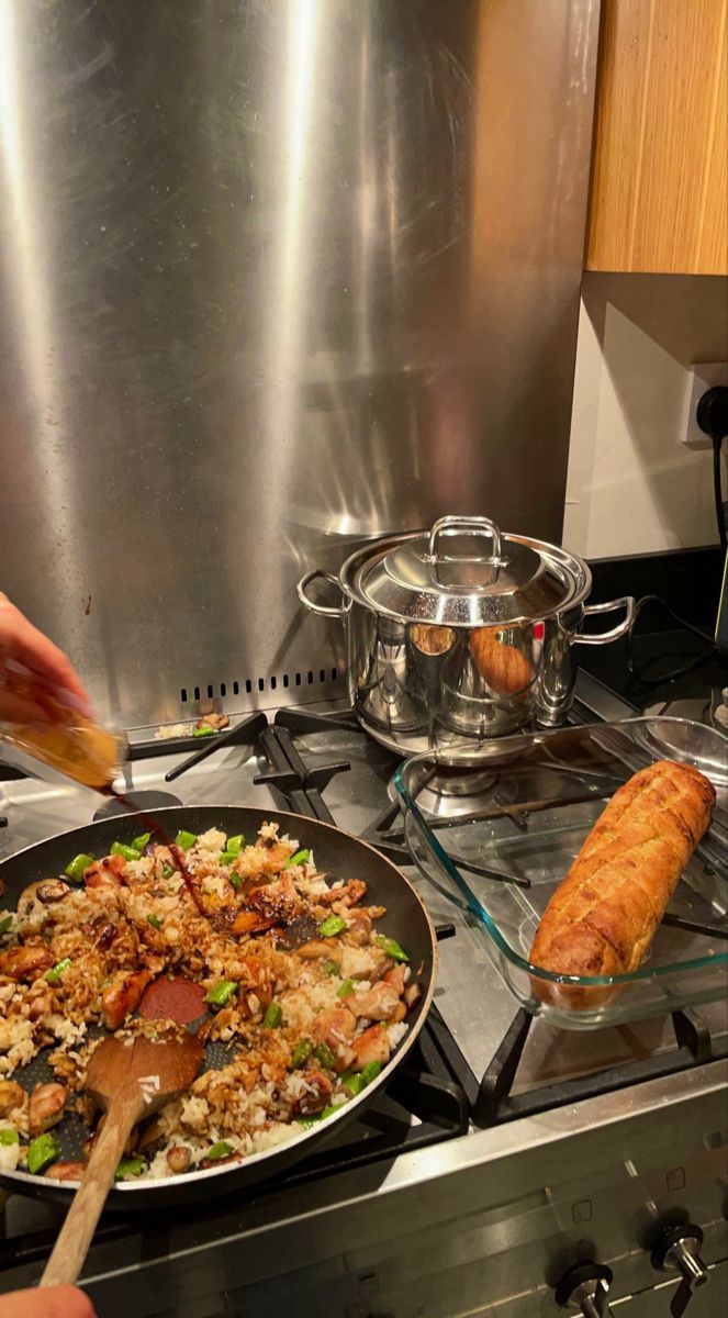 a person cooking food in a pan on top of a stove next to an oven