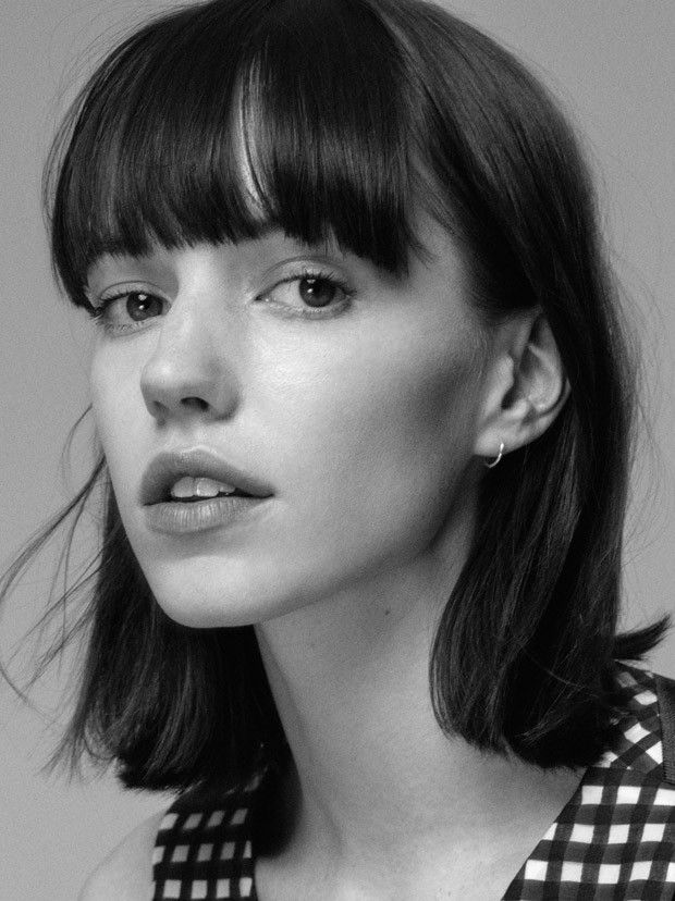 a black and white photo of a woman with short hair wearing a checkered shirt