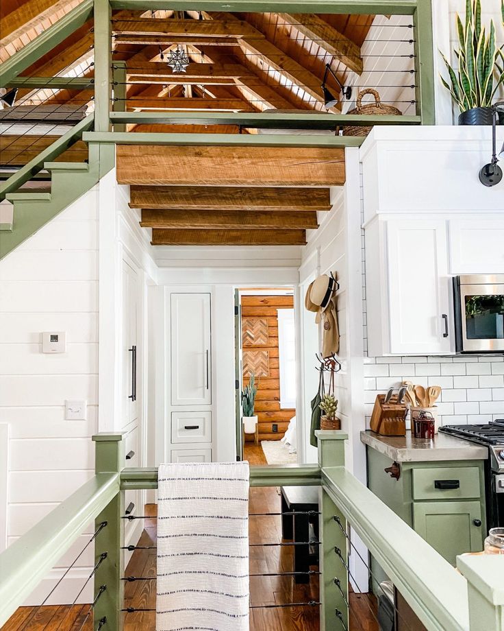 an open kitchen with green cabinets and white walls, along with wood flooring that matches the ceiling