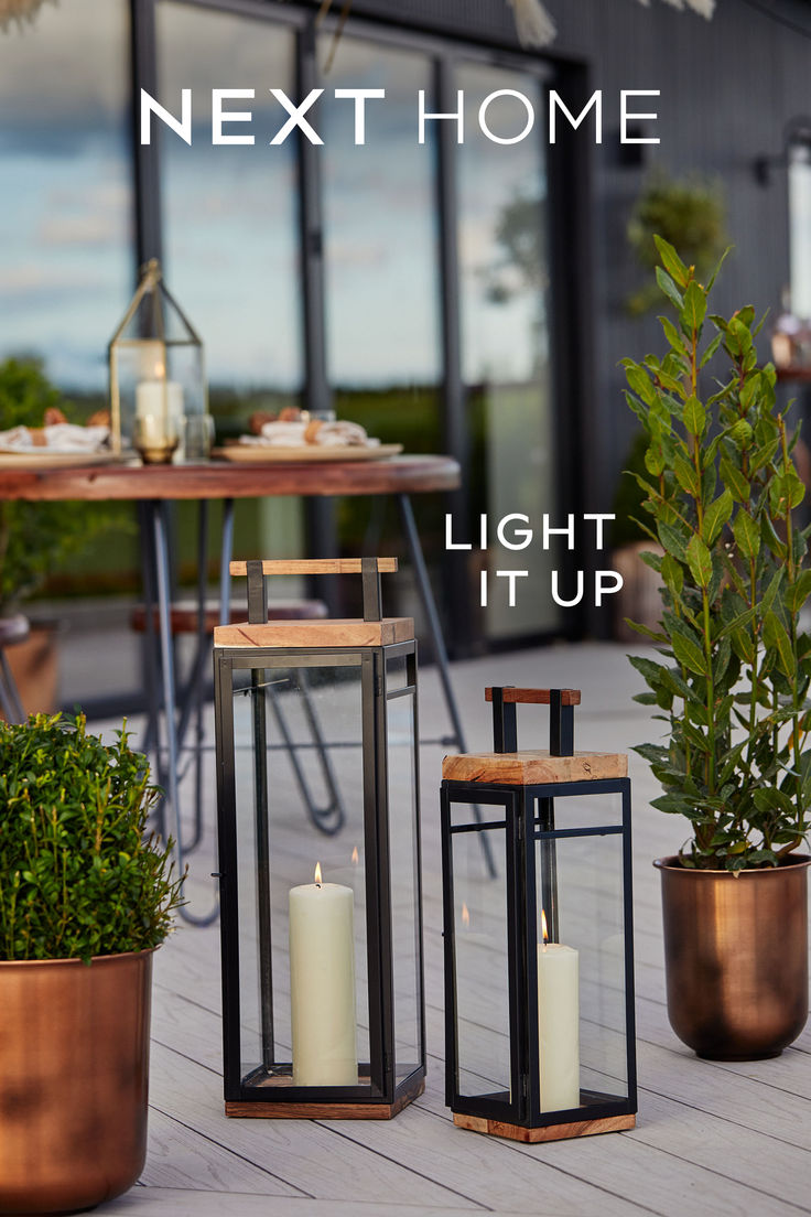 some candles are sitting on the ground next to potted plants