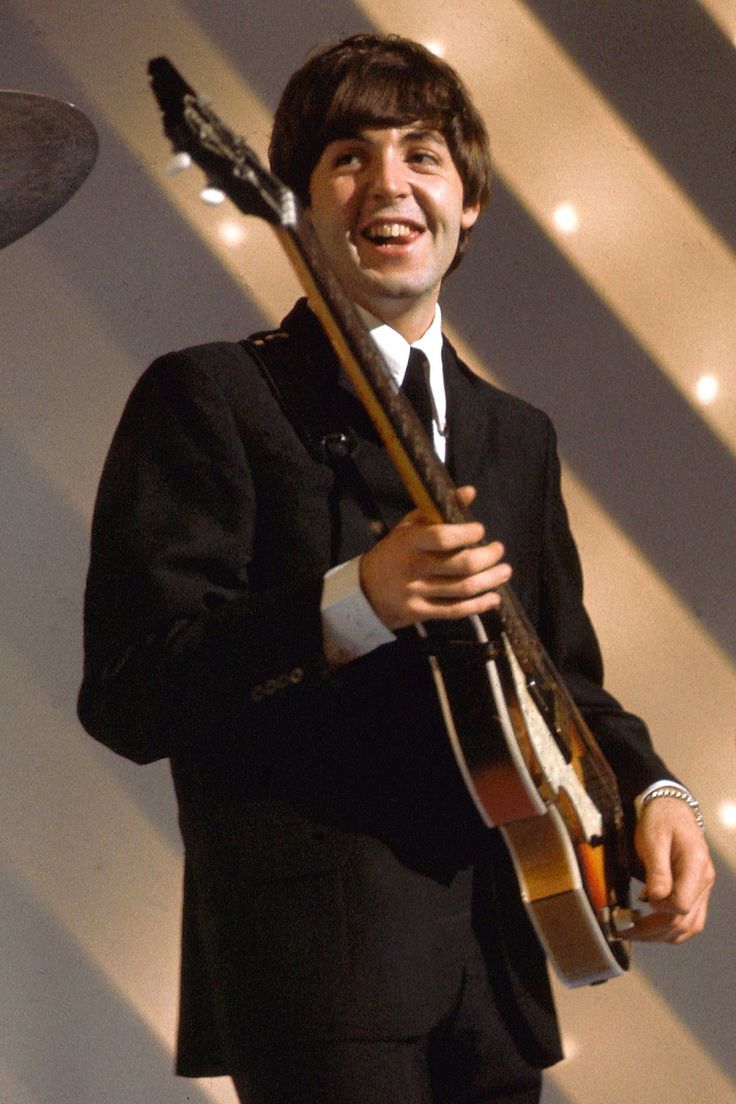 a man in a suit and tie holding a guitar