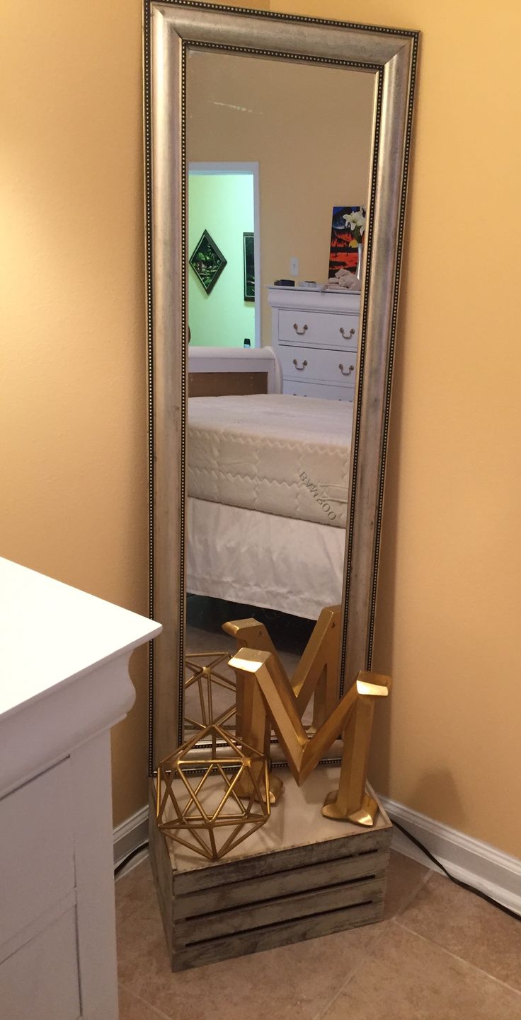 a large mirror sitting on top of a floor next to a white dresser and bed