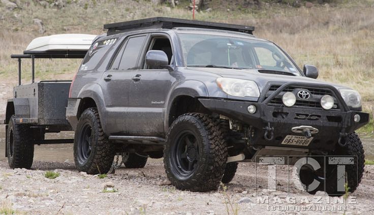 a gray four - doored vehicle driving on a dirt road