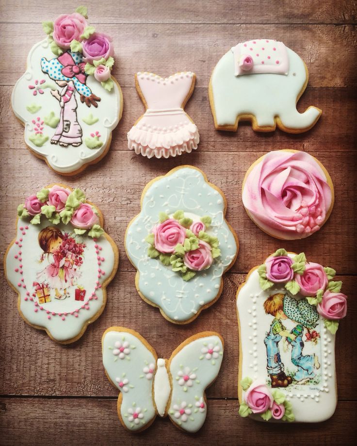 some decorated cookies on a table with pink flowers and other items in the shape of animals