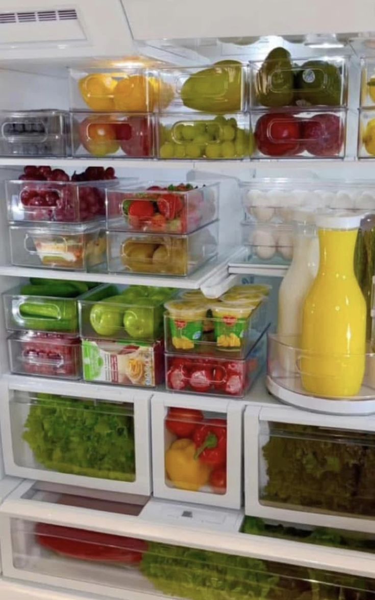 an open refrigerator filled with lots of different types of vegetables and fruit in plastic containers