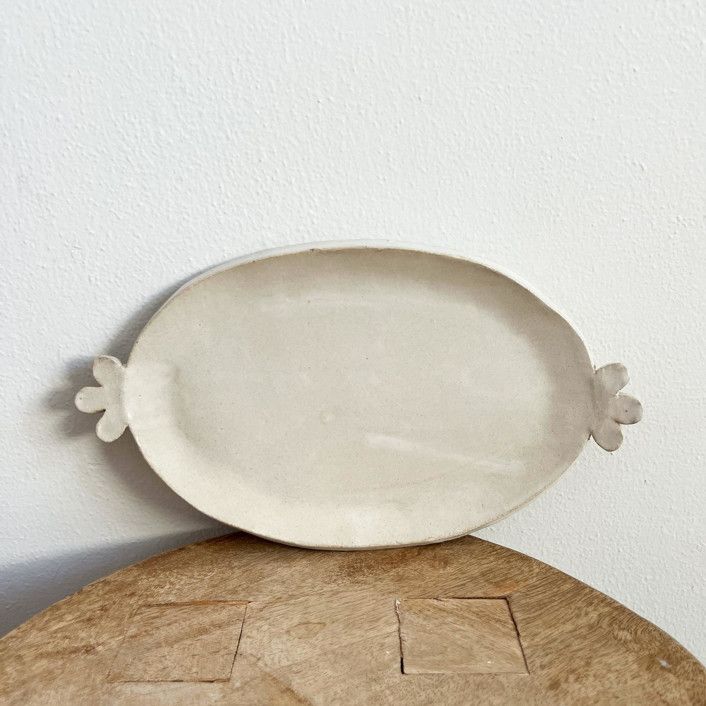 a white plate sitting on top of a wooden table next to a wall and floor