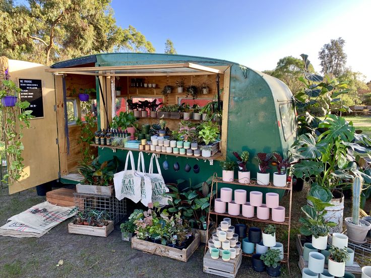 a green trailer with plants and potted plants on the outside, in front of it